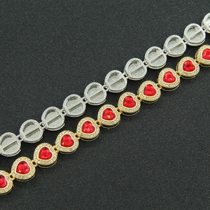 Macro detail of hip-hop cuban link bracelet showing red heart stones and diamond inlay