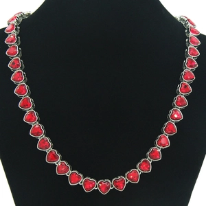 Close-up of red heart crystals linked on a silver chain displayed on a black velvet stand