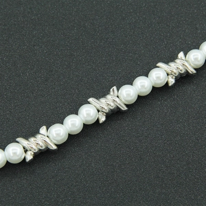 Macro detail of pearly beads and silver barbed wire link necklace on black background