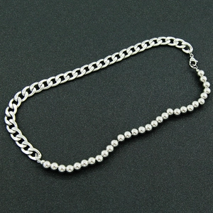 Silver tone curb chain and bead necklace with lobster clasp on dark textured background