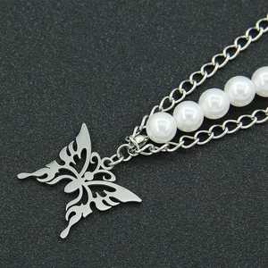 Detailed close-up of hollow butterfly pendant on silver pearl and Cuban chain necklace