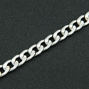 Macro shot of polished silver curb chain links on black textured surface with sharp detail