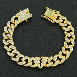 Macro detail of gold Cuban link bracelet with iced-out broken heart and secure box clasp