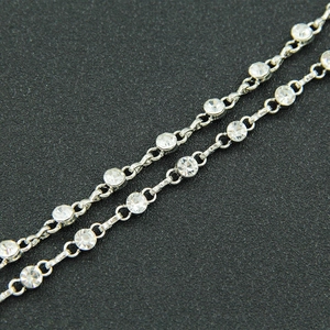 Close-up of a silver-toned metal chain featuring sparkling round-cut clear crystals