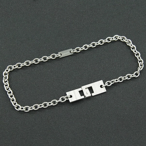 Silver stainless steel chain necklace with geometric interlocking clasp on grey surface