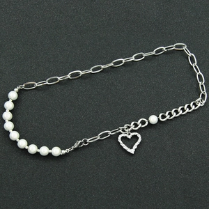 Asymmetric heart pendant necklace with pearls and titanium steel chain on black surface