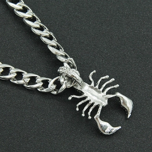 Gros plan d'un pendentif scorpion argenté avec strass sur une grosse chaîne cubaine