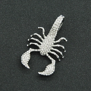 Détail macro du pendentif scorpion argenté orné de cristaux sur fond sombre