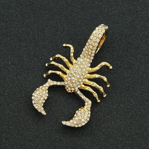 Gros plan d'un pendentif scorpion doré orné de strass blancs brillants sur fond noir