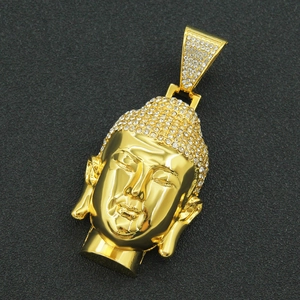 Macro shot of gold Buddha pendant with inlaid rhinestones on a textured black surface