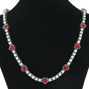 Detail view of silver necklace with red heart gems and round clear crystals on black bust