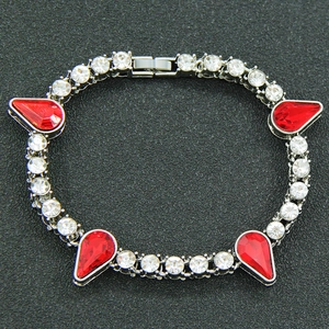 Détail d'un bracelet argenté orné de strass clairs et de gemmes rouges en goutte d'eau