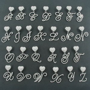 Macro shot of silver hip-hop letter pendants with heart clasp and iced-out rhinestones