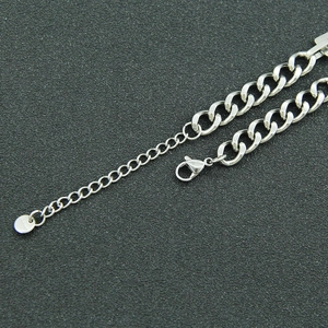 Detailed macro view of silver Cuban chain bracelet with lobster clasp and round metal tag