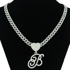 Macro view of iced out Cuban chain with heart clasp and crystal letter B pendant