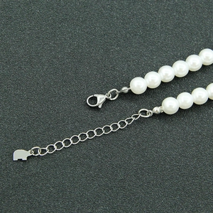 Silver link bracelet with white pearls and elephant charm displayed on a grey base