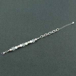 Detail view of pearl and silver chain bracelet featuring lobster clasp and extension chain