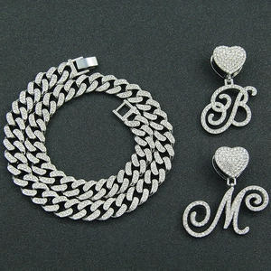 Macro view of iced out Cuban link chain with cursive letter pendants B and M
