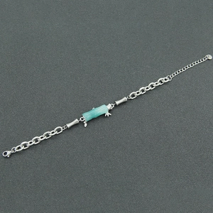 Detail of bamboo joint bracelet with green bead and silver chain on grey background
