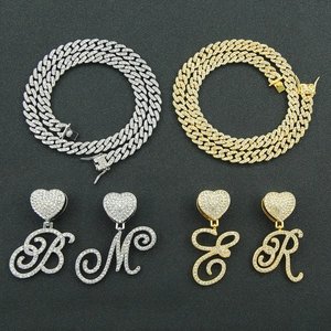 Close-up of iced out heart letter pendants and heavy cuban link chains in gold and silver