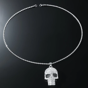 Macro view of iced out skull pendant with clear crystals and silver rope chain
