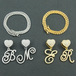 Detailed view of hip hop capital letter pendants with sparkling crystals on rope chains