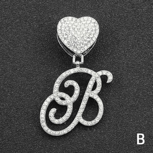 Macro detail of silver tone iced out letter B pendant with heart clasp and clear crystals