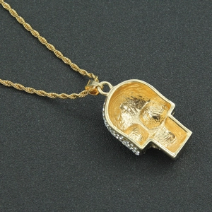 Macro shot of gold-plated hip hop skull pendant with white rhinestones and rope chain