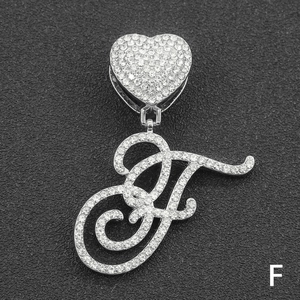 Macro shot of silver letter F pendant with iced-out heart clasp on black display