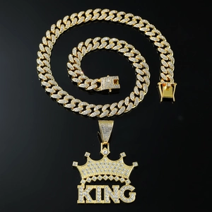 Detailed close-up of iced-out gold KING crown pendant on a shiny cuban link chain