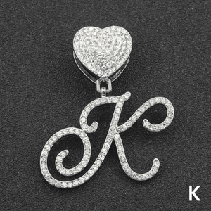 Detail of iced out letter K pendant with heart clasp and crystal paving on black background