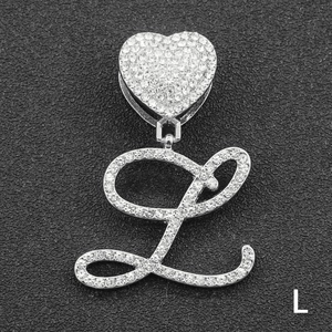 Macro shot of a silver iced-out cursive letter L pendant with a heart-shaped clasp