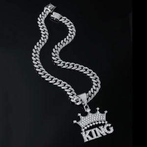 Macro detail of iced-out silver King crown pendant with silver cuban link chain