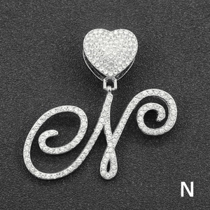 Macro shot of silver letter N pendant with iced out rhinestones and heart clasp