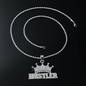 Macro shot of iced-out HUSTLER crown pendant with sparkling stones on silver rope chain