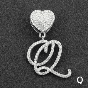Close-up of heart-shaped pendant with iced-out cursive letter Q and micro-pave crystals
