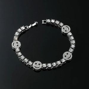 Gros plan d'un bracelet de strass argenté avec visages souriants sur fond noir