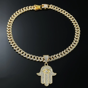 Détail du pendentif Main de Fatma avec œil maléfique sur une grosse chaîne cubaine dorée