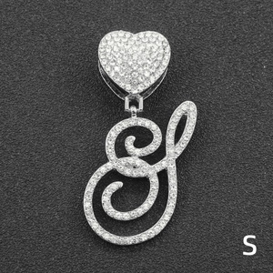 Close-up of iced out heart clasp and cursive letter S pendant with silver tone rhinestones