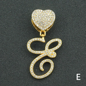 Macro shot of gold-plated letter E pendant with crystal pavé and heart-shaped bail