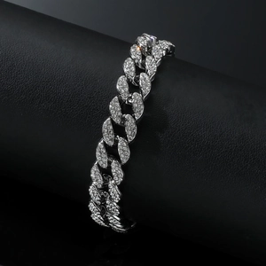 Macro shot of a sparkling silver Cuban link anklet with dense rhinestones on a black roll