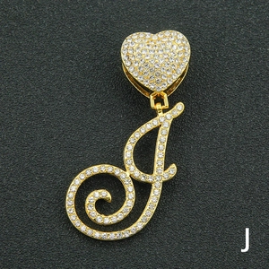 Macro shot of gold-plated cursive letter J pendant with micro-pave crystals on black background