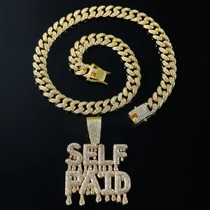 Close-up of a gold-plated Cuban link chain with 'SELF PAID' iced-out rhinestone pendant