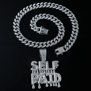 Macro shot of silver hip-hop Cuban chain and dripping SELF PAID letter pendant with crystals