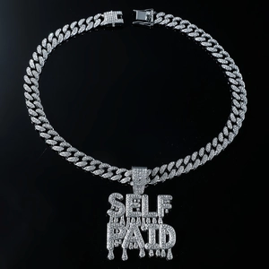 Macro view of iced out silver Cuban chain with shimmering SELF PAID drip letter pendant