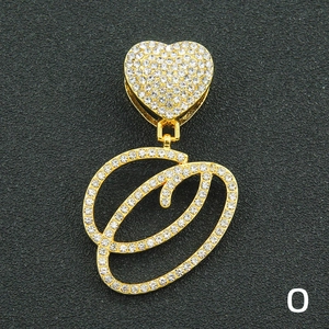 Macro view of gold-plated iced out cursive letter O pendant with heart buckle detail