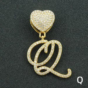 Close-up of iced out gold plated letter Q pendant with iced heart clasp and cubic zirconia