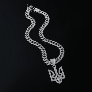 Close-up of iced out silver Cuban link necklace with sparkling trident Tryzub pendant