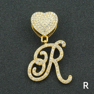 Close-up of iced out golden letter R pendant with heart-shaped bail and paved crystals