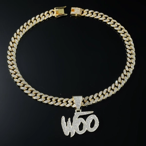 Close-up of golden Cuban link chain with iced out WOO letter pendant and double safety clasp